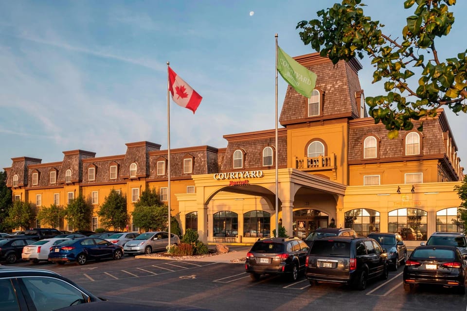 A Courtyard by Marriott hotel at golden hour, with flags flying over the entrance